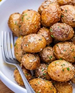 air fried potatoes added into a bowl with parmesan cheese and chopped parsley.
