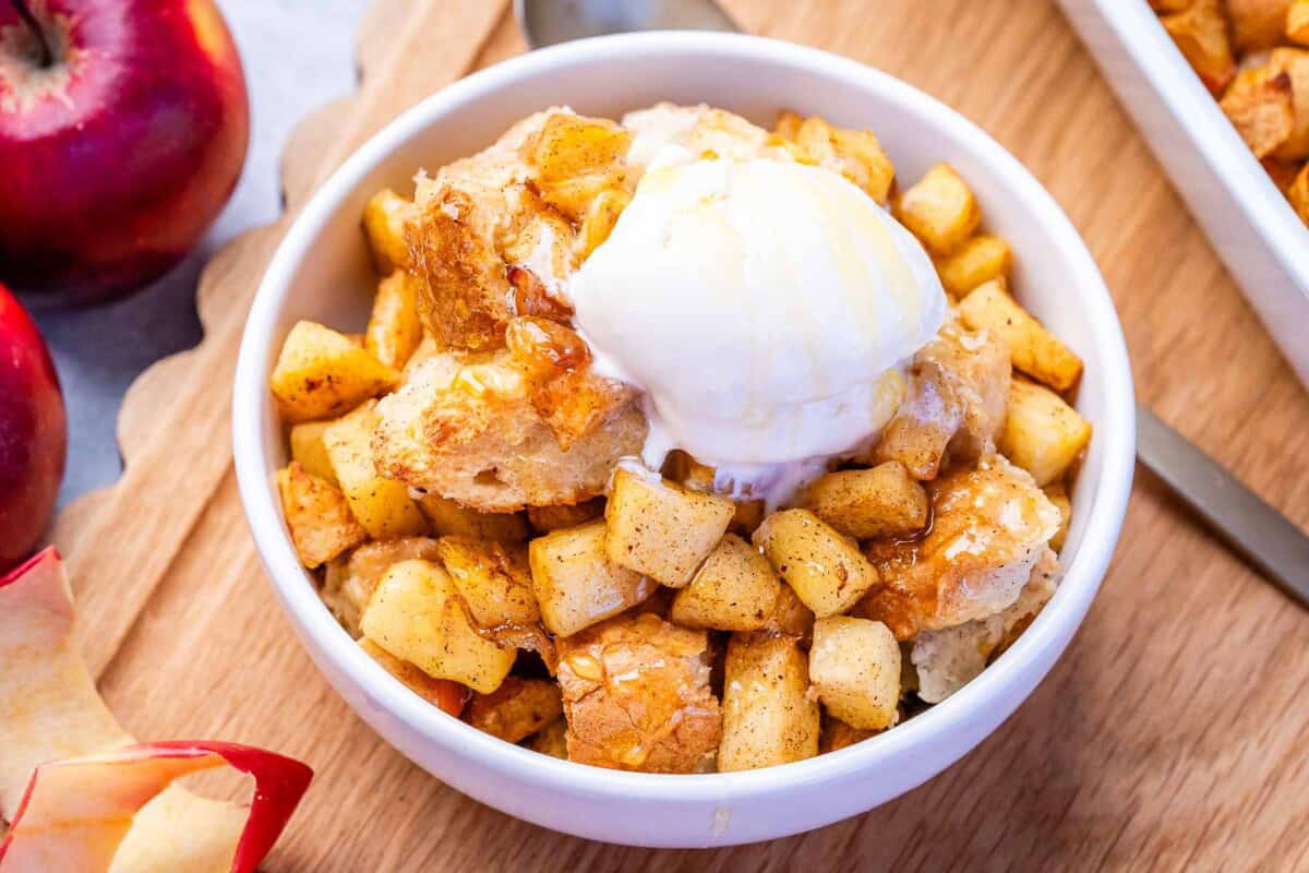 apple pudding served in a bowl and topped with a serving of vanilla icecream.