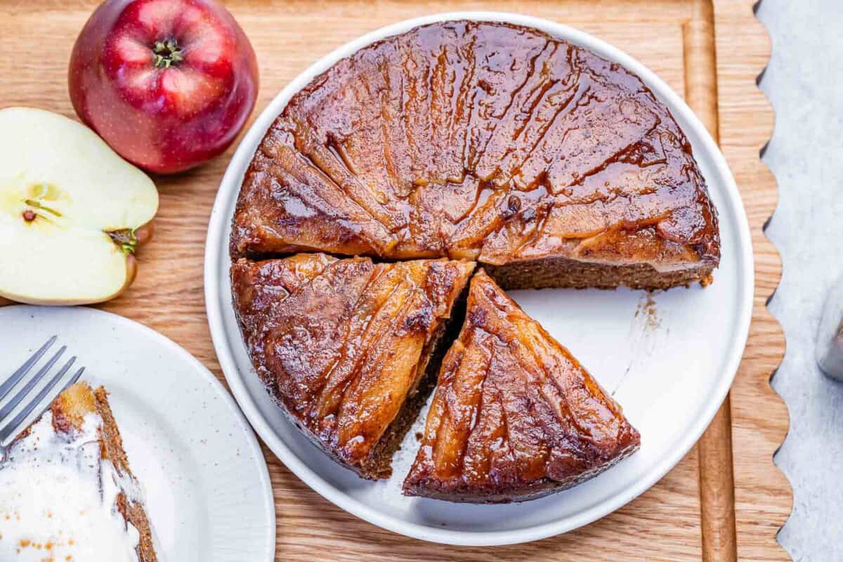 An apple upside-down cake sliced on a plate.