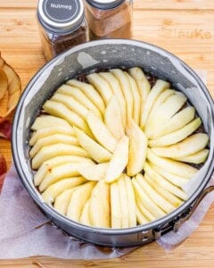 adding the sliced apples in the pan for making cake.