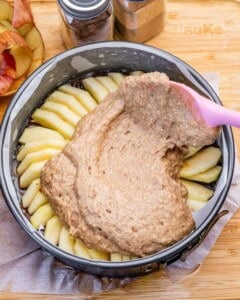 adding the date cake better over the apples in a pan.