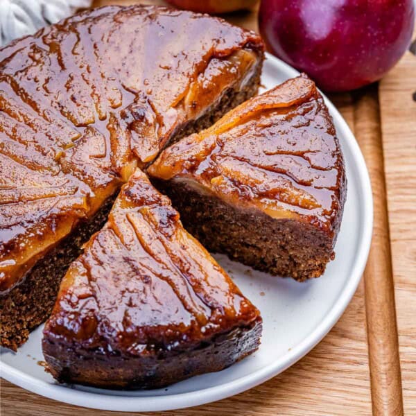 upside down apple cake on a plate with 2 slices cut off.