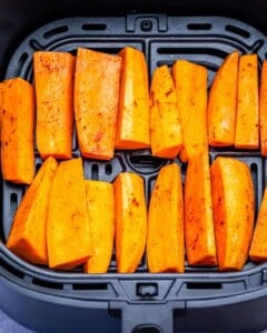 placing potato wedges in an sir fryer.
