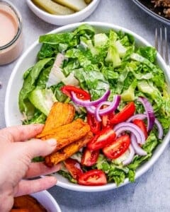 assembling the burger bowl with the veggies and sweet potatoes.