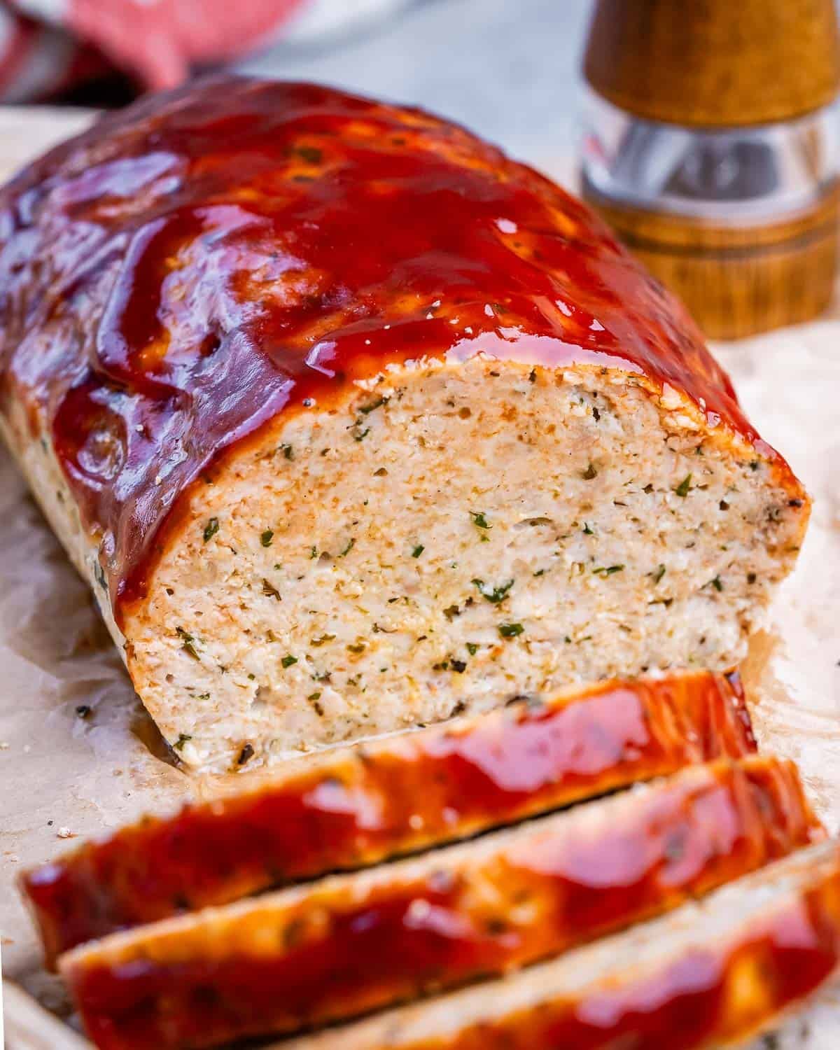 A loaf of chicken meatloaf glazed with bbq sauce which has been sliced.