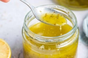 spooning some salad dressing from the jar.