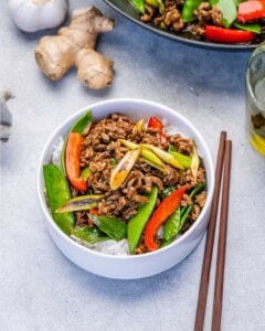 Beef stir fry served over rice in a round bowl.