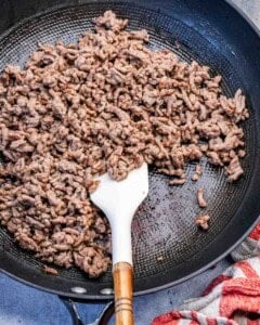cooking seasoned ground beef in a skillet.