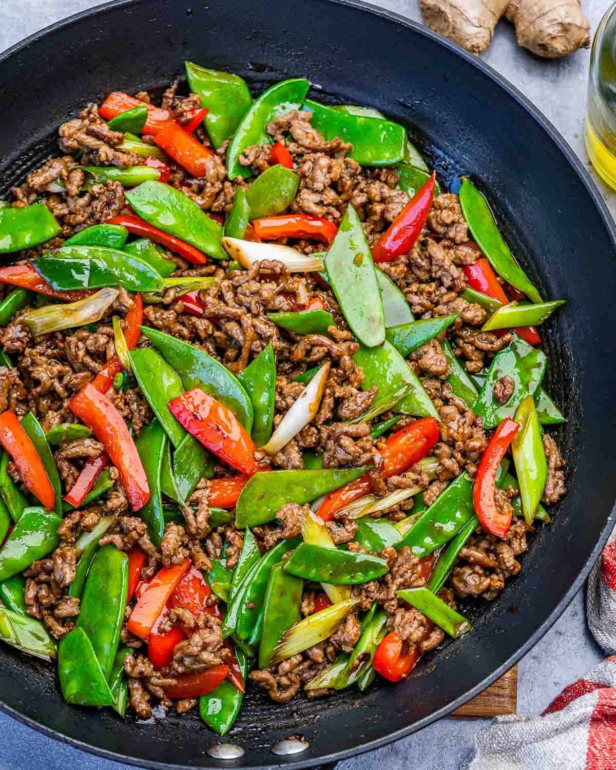 ground beef stir fry with snap peas in a skillet.