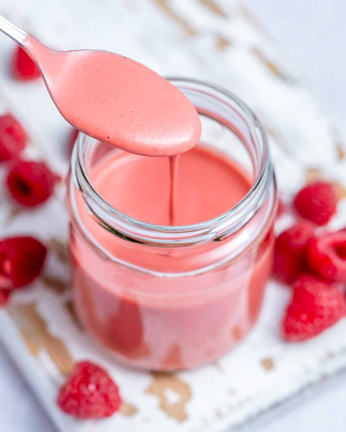 A jar filled with raspberry vinaigrette with spoon in jar. 