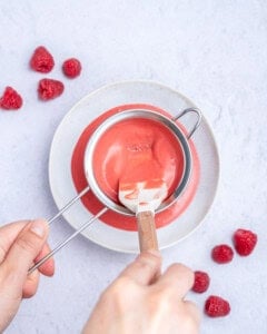 straining the raspberry seeds in a strainer for the dressing.