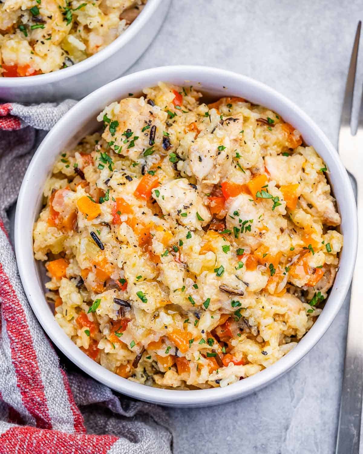 A white bowl of slow cooker chicken and rice next to a striped napkin.
