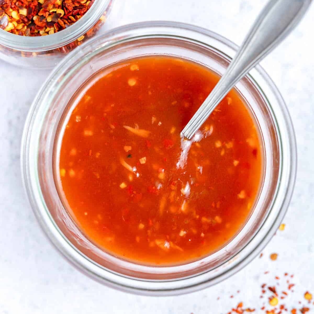 sweet chili sauce in a jar with spoon in the jar.