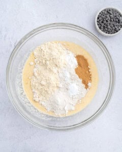 adding the flour and cinnamon over the wet batter to make the muffin batter.