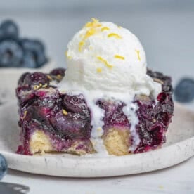 a slice of blueberry cobbler on a plate topped with a serving of ice cream.