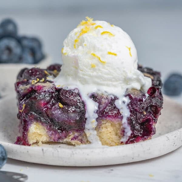 a slice of blueberry cobbler on a plate topped with a serving of ice cream.