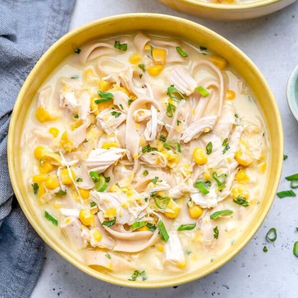 a yellow round bowl filled with chicken corn soup made with noodles