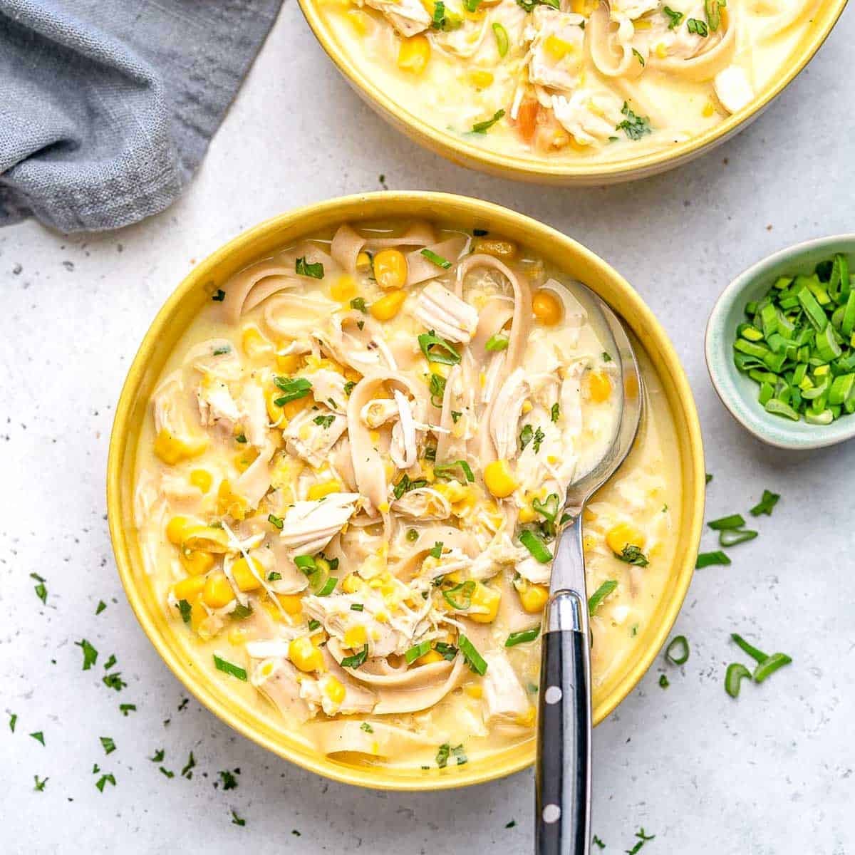 a bowl with chicken corn and noodle soup with spoon in the bowl.