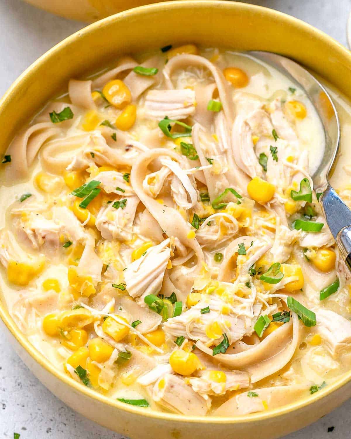 a bowl with a creamy looking chicken and corn soup with noodles.
