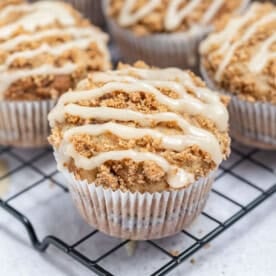 cinnamon coffee cake muffin topped with cinnamon sugar glaze on a wire rack.