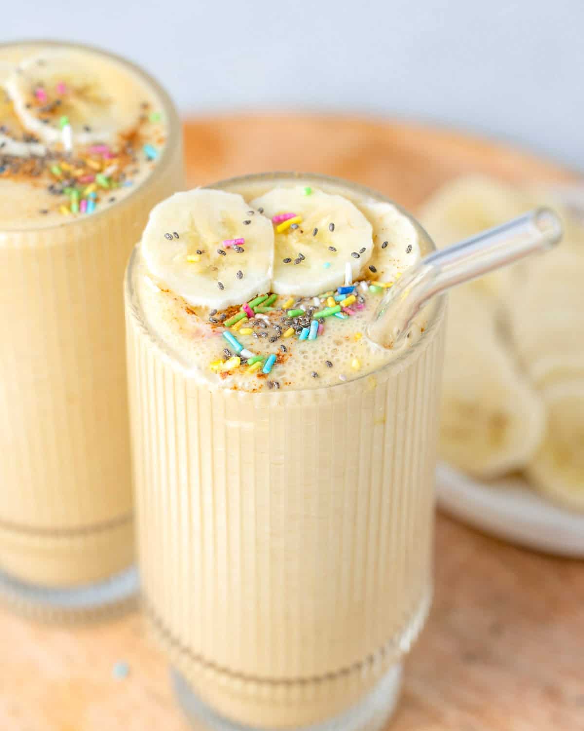 two vanilla shakes in cups on a wooden board.