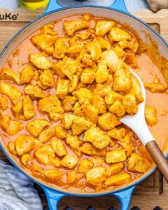 a pan with chicken korma and a spoon in it.