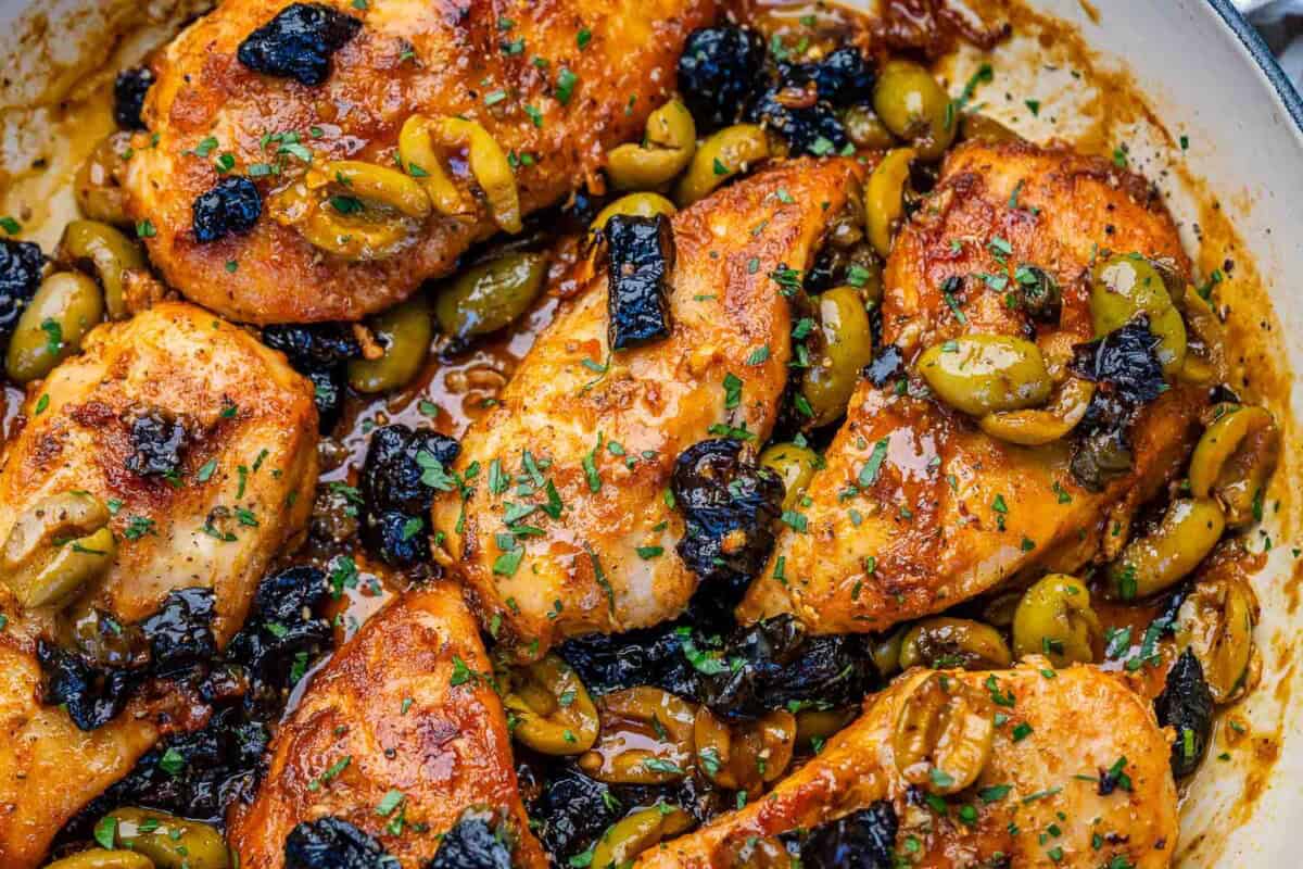 cooked chicken marbella with prunes and olives in a skillet.