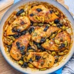 cooked chicken breasts in an olive sauce in a skillet.
