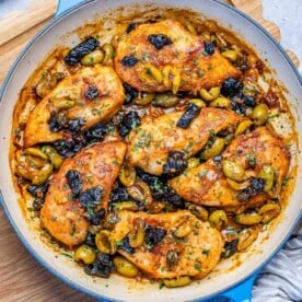 cooked chicken breasts in an olive sauce in a skillet.