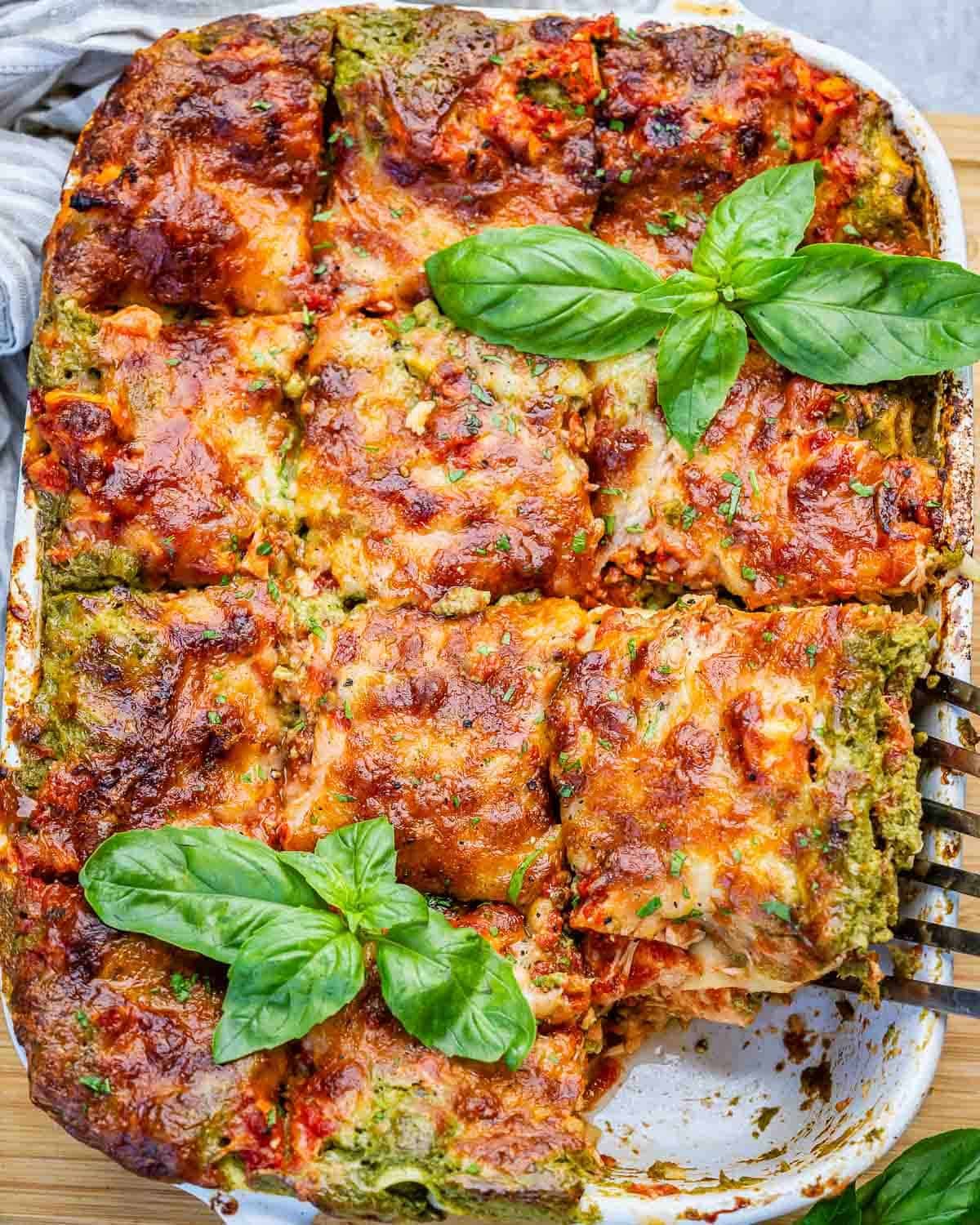 A chicken lasagna in a white dish with a spatula lifting out a slice.