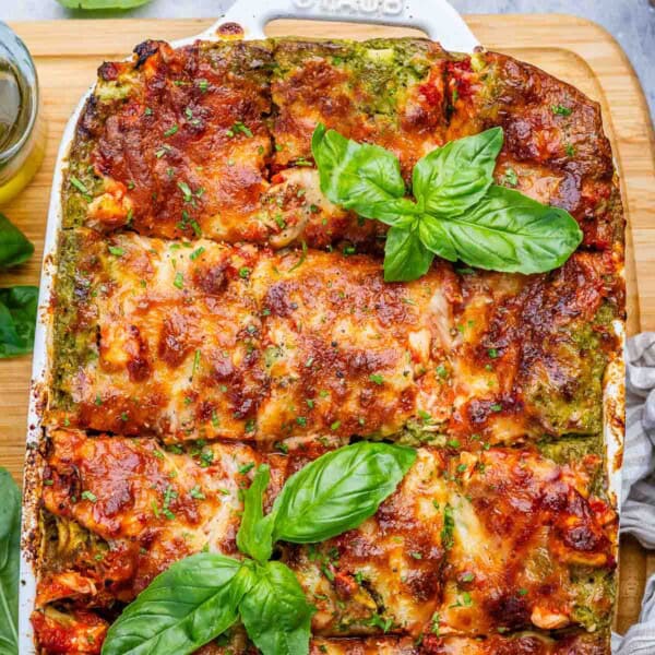 chicken lasagna in a dish topped with some fresh basil leaves.