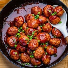 meatballs in a grape jelly tomato sauce in a skillet.