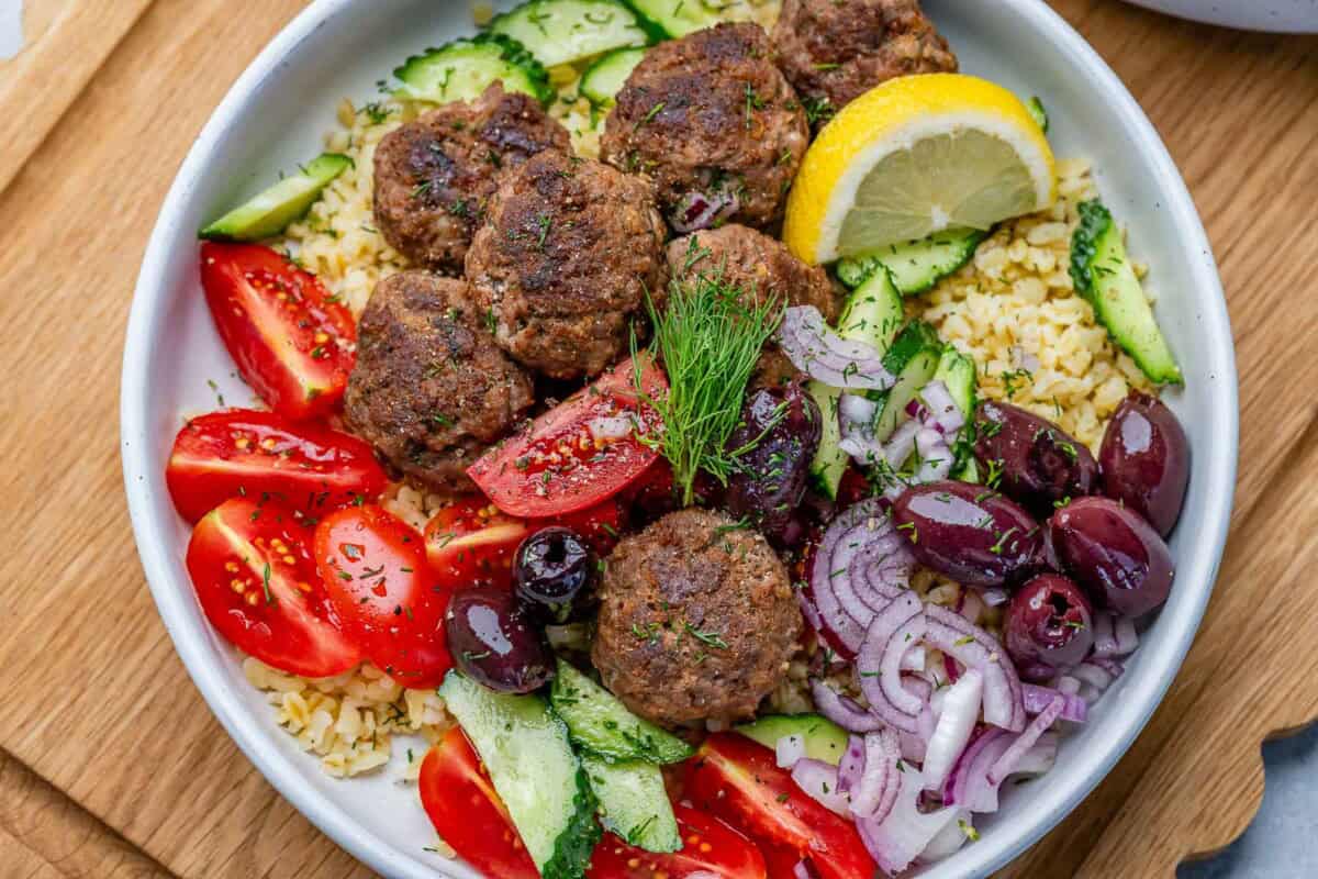 greek meatballs served in bowl with salad and kalamata olives.