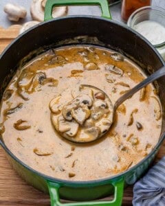 A green pot of Hungarian mushroom soup with a ladle in it