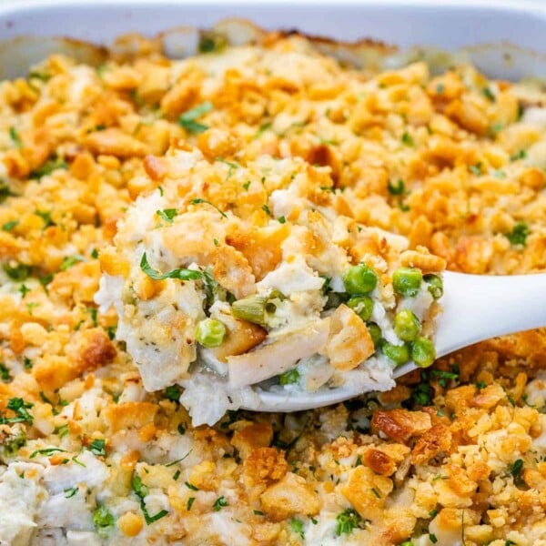 million dollar chicken casserole in a dish with a spoon full serving.