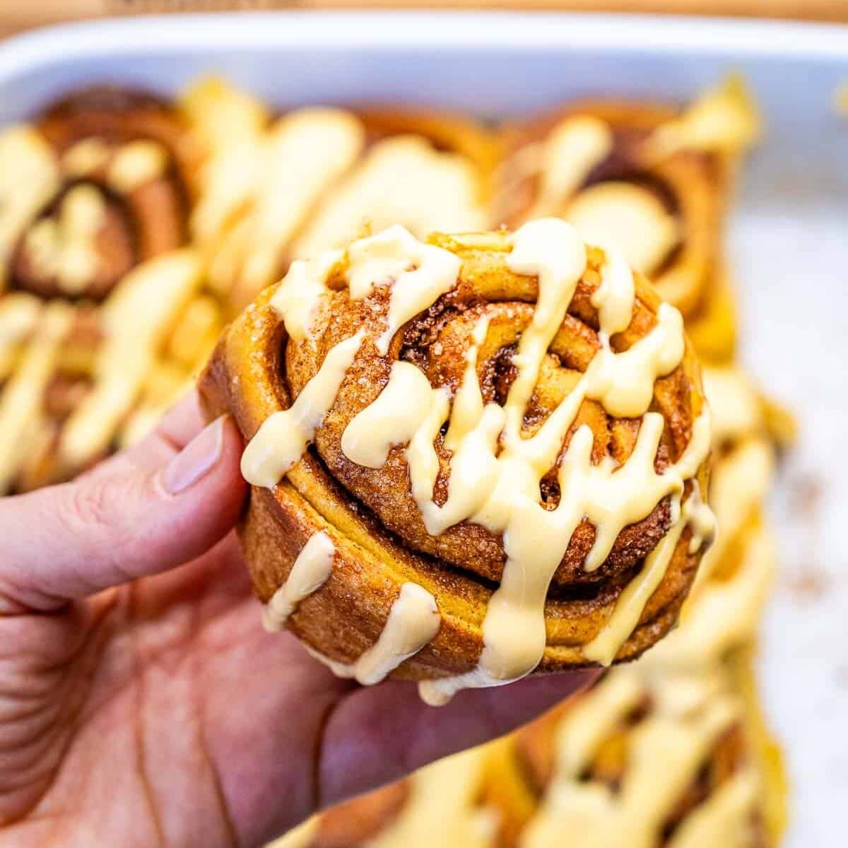 hand holding a pumpkin cinnamon roll.