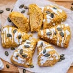 pumpkin scones cut up, baked and drizzled with sugar glaze and topped with pumpkin seeds.