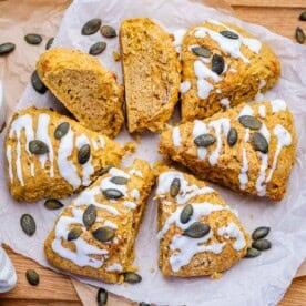 pumpkin scones cut up, baked and drizzled with sugar glaze and topped with pumpkin seeds.