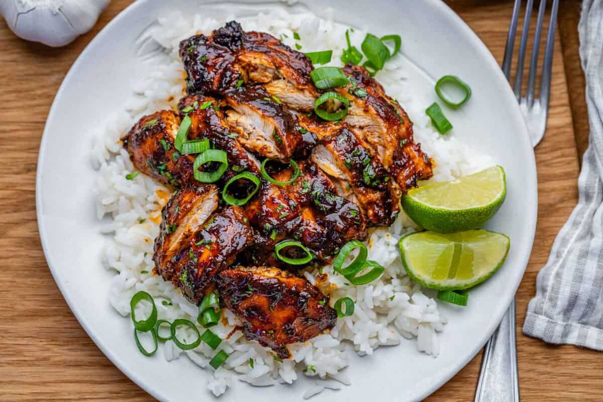 slow cooker chicken thighs cooked in chipotle sauce served over a plate of rice and topped with fresh sliced green onions.