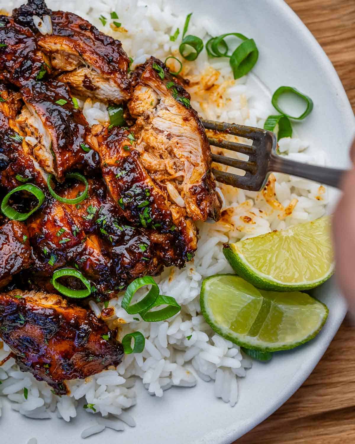 chicken thighs cooked in a slow cooker sliced  and served over a plate of rice.