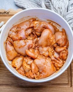 Seasoned chicken thighs in a bowl.