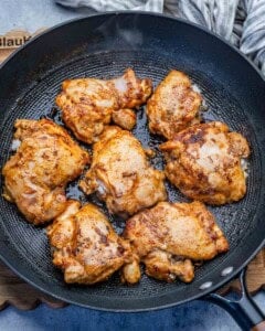 seared chicken thighs on a skillet.