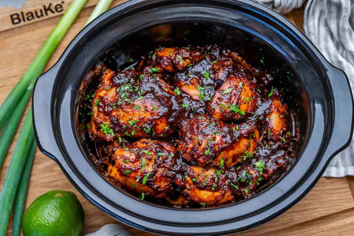slow cooker chicken thighs topped with fresh onion garnish.