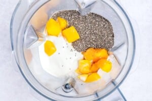 ingredients for mango smoothie added to a blender.