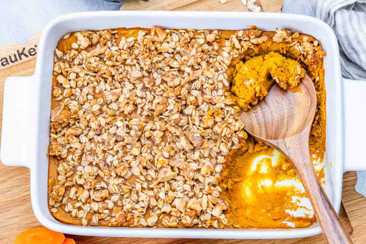 a baking dish with carrot souffle and a serving spoon in the dish.