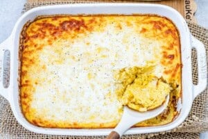 corn pudding in a casserole dish with a serving spoon in the dish.