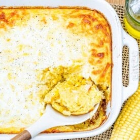 corn pudding in a casserole with a spoon in the dish.