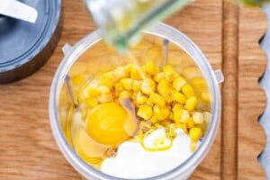 adding the corn, milk, yogurt and eggs in a blender to blend.