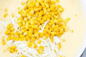 adding corn and gruyere over the corn pudding batter.