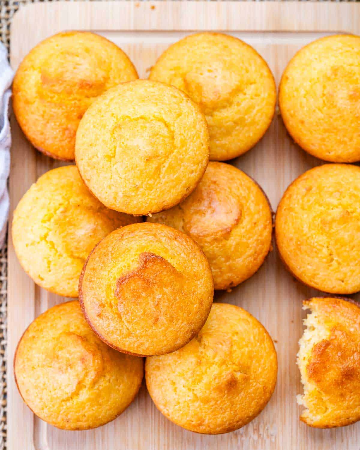 A wooden board with a pile of baked cornbread muffins.